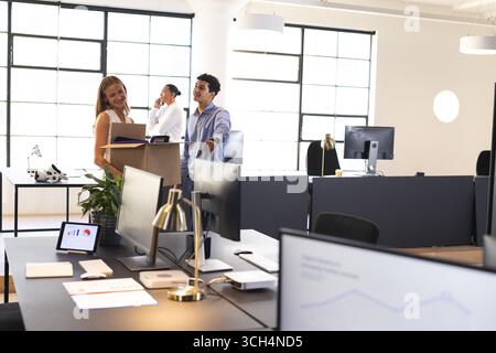 Colleagues discussing project in modern office, smiling and collaborating together Stock Photo