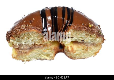 Chocolate topping and dark chocolate sauce and hazelnut pieces on a ring donut, a glazed, yeast raised, American style ring doughnut, type of food mad Stock Photo