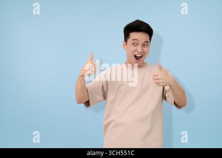 young man making thumbs up gesture in studio background Stock Photo