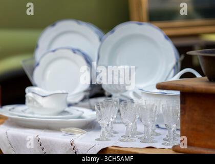 Flea market vintage things counter with crystal glasses and other old things. Different antiques on flea market. Stock Photo