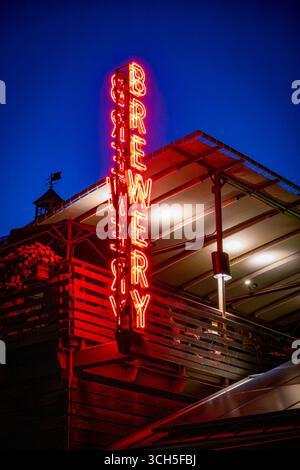 Northampton, MA - US - Aug 22, 2025 Glowing red neon “BREWERY” sign illuminates the night sky above a modern rooftop bar, creating a bold and inviting Stock Photo