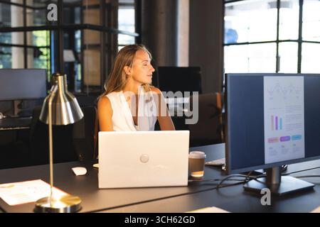 Analyzing data on computer screen, businesswoman working late in office, looking thoughtful Stock Photo