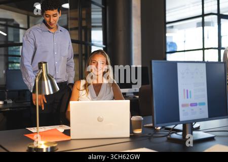 Collaborating in modern office, colleagues discussing project details using laptop Stock Photo
