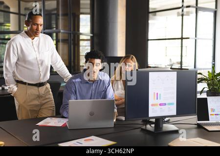 Business team collaborating on laptop and reviewing data charts in modern office Stock Photo
