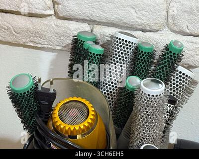 Collection of round hair brushes and a yellow hair dryer in a salon. Hairstyling, professional tools, and beauty care equipment. Stock Photo