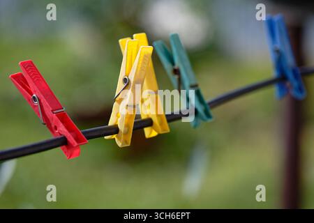 Close-up of clothespins hanging on a wire against a blurred green natural background, spring or summer outdoor concept. Stock Photo