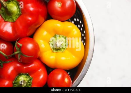Fresh peppers and tomatoes in bowl. Red and yellow vegetables on white background. Healthy organic ingredients for cooking. Natural vitamins. Stock Photo