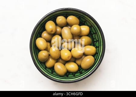 Fresh green olives in ceramic bowl. Mediterranean food ingredient. Closeup of healthy snack on white background. Organic diet nutrition source. Stock Photo