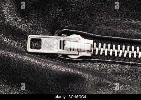 Metal zipper on black leather closeup. Fashion accessory detail with textile texture. Clothing design element for jacket or bag. Modern style material Stock Photo