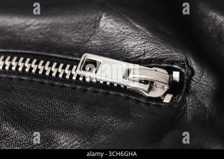 Zipper closeup on black leather. Metal fastener detail for clothing accessory. Fashion textile background. Stylish garment element. Stock Photo