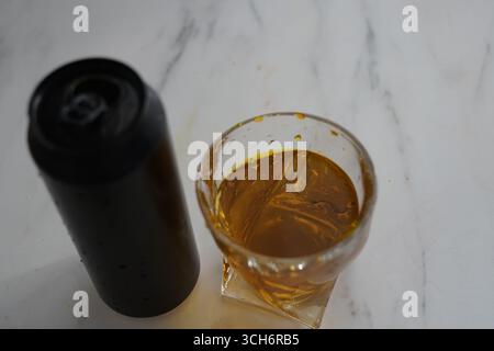 Glass of Golden Beverage with Black Container on Marble Surface Stock Photo