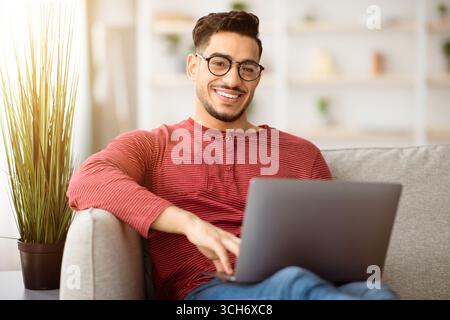 Positive arab man freelancer working from home, using notebook Stock Photo