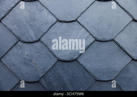 Overlapping slate roof tiles create textured pattern, showcasing craftsmanship in home construction Stock Photo