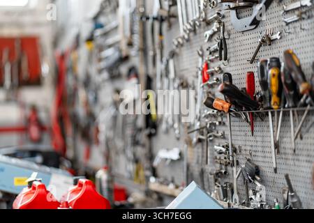 Various hand tools organized on pegboard in workshop. Screwdrivers, wrenches, and pliers neatly arranged for easy access, creating a functional workspace in garage  Stock Photo