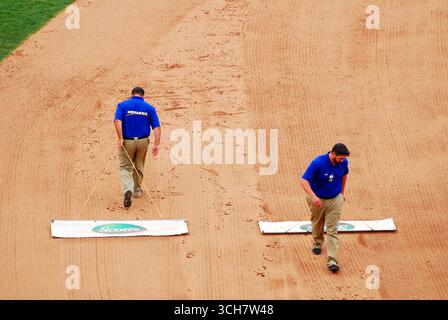 Grounds crew smooths out the infield dirt on a baseball field between innings Stock Photo