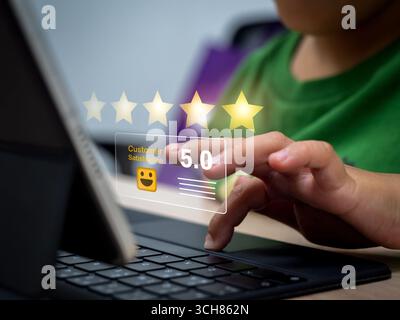 Child using tablet with virtual 5 star rating interface, representing kids and technology, online reviews, customer satisfaction, digital feedback, ga Stock Photo