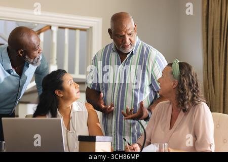 Senior colleagues discussing project ideas around laptop in modern office setting. Business, teamwork, brainstorming, collaboration, strategy, innovat Stock Photo