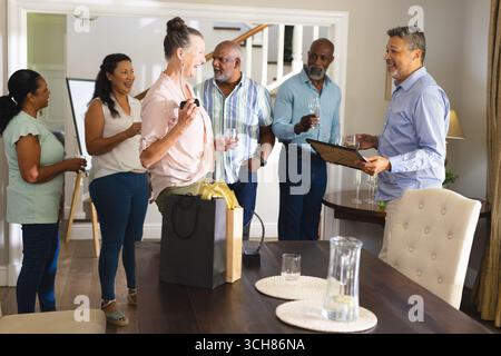 Diverse Senior Friends celebrating at home, enjoying conversation and drinks with friends. Elderly, friendship, party, lifestyle, celebration, gatheri Stock Photo
