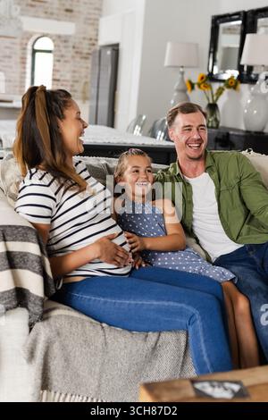Happy family relaxing on couch at home, laughing and enjoying time together Stock Photo