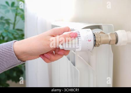 The heat regulator on the radiator of the house. A woman regulates the heat level in the radiator Stock Photo