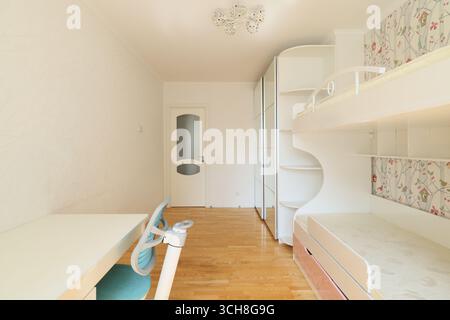A Cozy and Minimalist Bedroom featuring Bunk Beds along with a Dedicated Study Space for kids Stock Photo
