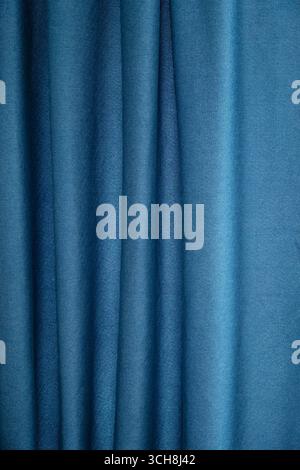 Dark teal fabric gently draped with vertical folds. Abstract background texture for textile design or artistic concept. Stock Photo