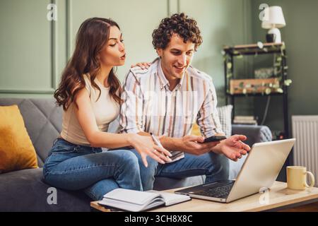 Couple holding financial documents while sitting in a cozy home setting. They discuss investments, savings, and budget while maintaining a positive an Stock Photo