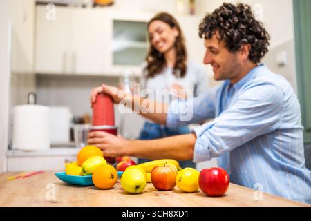 A smiling husband and wife prepare a nutritious fruit drink using a blender, embracing a fun, healthy lifestyle. Stock Photo
