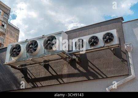 Industrial cooling units with big ventilation fans installed on an urban structure. Selective focus. Stock Photo