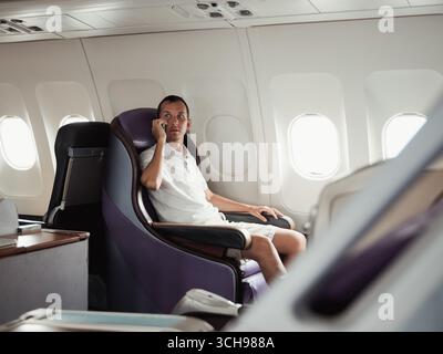 Traveler relaxing in a premium seat on an airplane during flight Stock Photo