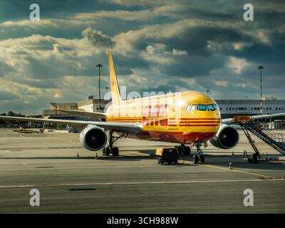 A DHL cargo plane parked on the tarmac under a cloudy sky in Milan Malpensa International airport in Italy. Stock Photo