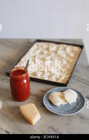 Cheese Topping on Unbaked Pizza Dough in Baking Pan Stock Photo