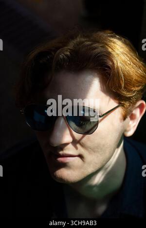 Young man relaxes in shaded area wearing sunglasses Stock Photo