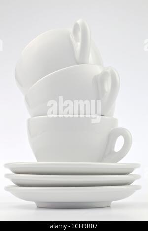 three white classic capuccino cups stacked with saucers below on the bottom Stock Photo