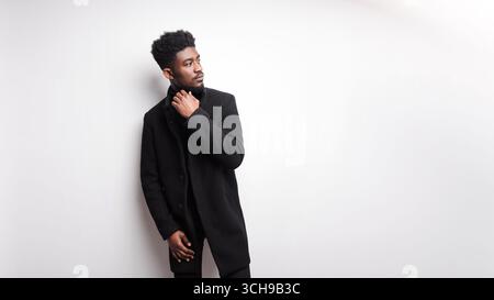 Serious young guy in black clothes looking away at white background Stock Photo