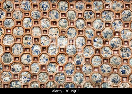 A decorative wall in the Imperial City of Hue, Vietnam, features a geometric mosaic made from embedded blue-and-white ceramic shards, reflecting tradi Stock Photo