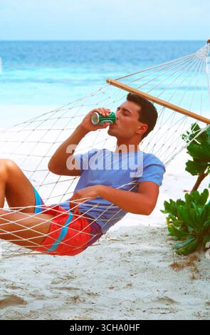 Maldives. Young man relaxing in hammock on tropical beach. Stock Photo