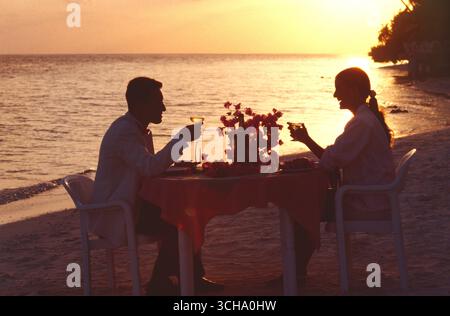 Maldives. Young couple having dinner on tropical beach at sundown. Stock Photo