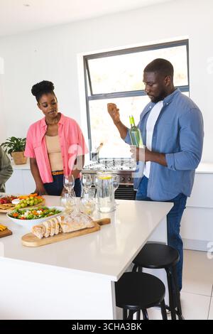 Friends enjoying wine and conversation in modern kitchen during casual gathering. socializing, lifestyle, dining, beverage, leisure, celebration Stock Photo