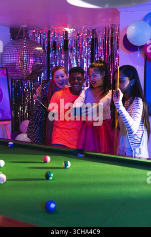Diverse Teenage friends celebrating at party, taking selfie near pool table with balloons, at home. celebration, friendship, Teenage diverse friends, Stock Photo