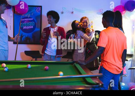 Diverse Teenage friends celebrating birthday with pool table, balloons, and hugs at party, at home. celebration, Teenage diverse friends, friendship, Stock Photo