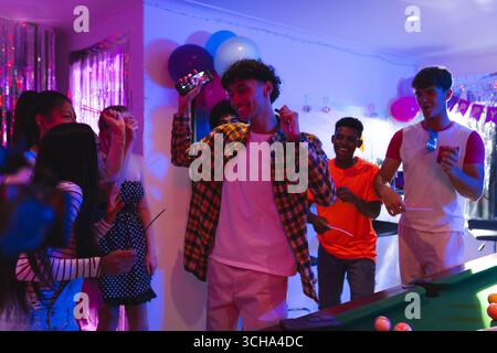 Teenage diverse friends dancing joyfully at home party, celebrating with friends and music. celebration, youth, friendship, excitement, gathering, enj Stock Photo