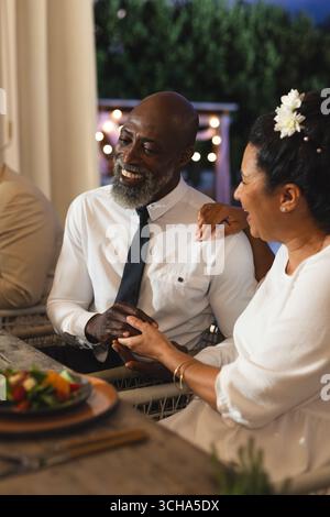 At wedding, Couple having dinner together at outdoor celebration, sharing joyful moments. outdoors, togetherness, happiness, festivity, gathering Stock Photo