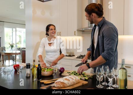 Couple preparing meal together in modern kitchen, smiling and enjoying conversation, at home. Cooking, lifestyle, food preparation, relationship, home Stock Photo