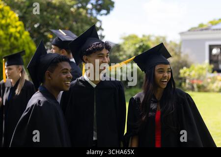 Teen graduates in caps and gowns celebrating joyfully outdoors with friends. Graduation, celebration, friendship, achievement, success, academic Stock Photo