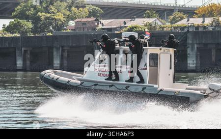 Special police units on a boat during a tactical operation, officers wearing balaclavas, uniforms and carrying automatic weapons. Stock Photo