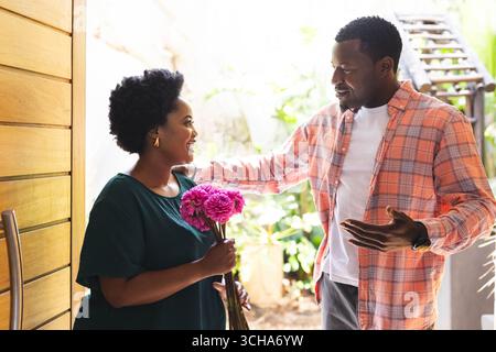 Smiling couple exchanging flowers at home, enjoying warm and friendly moment, copy space. love, romance, friendship, gesture, happiness, lifestyle Stock Photo