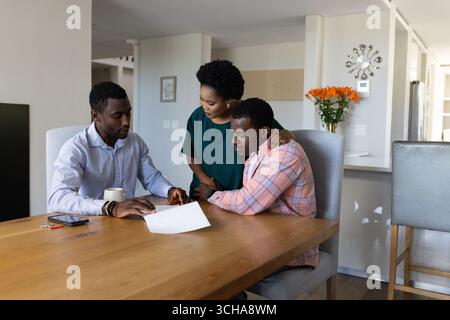 Discussing documents, friends collaborating on project with focus and teamwork at home. Collaboration, brainstorming, productivity, togetherness, home Stock Photo