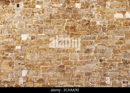 Old brick wall with faded colors, weathered surface, and irregular pattern, offering rustic texture for backgrounds, design, or architectural referenc Stock Photo