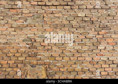 Weathered brick wall surface with irregular patterns and aged textures, perfect for backgrounds or architectural design Stock Photo